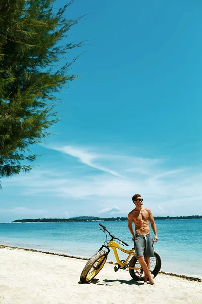 Schöner Mann mit Fahrrad Sonnenbräune am Strand. Sommerferien. — Stockfoto