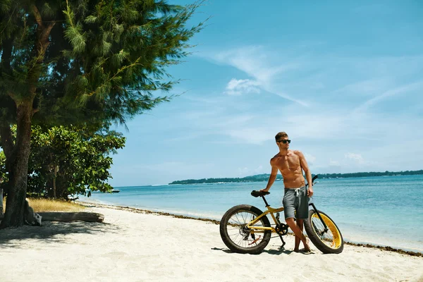 Schöner Mann mit Fahrrad Sonnenbräune am Strand. Sommerferien. — Stockfoto
