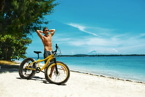 Schöner Mann mit Fahrrad Sonnenbräune am Strand. Sommerferien. — Stockfoto