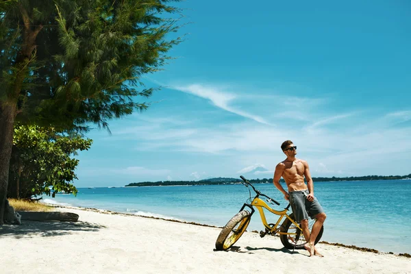 Bel homme avec vélo soleil bronzage sur la plage. Vacances d'été . — Photo