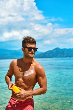 Man Tanning Using Sun Block Body Cream On Summer Beach