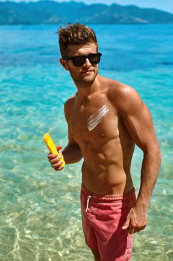 Sexy Man Tanning Using Sunscreen Cream On Body Skin. Summer 