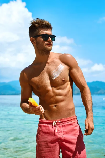 Homem bronzeando usando Sun Block Body Cream na praia de verão — Fotografia de Stock
