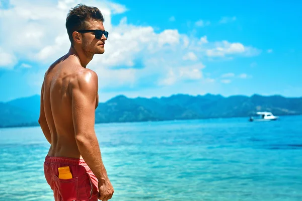 Bronzage homme sexy avec crème solaire sur la plage d'été . — Photo