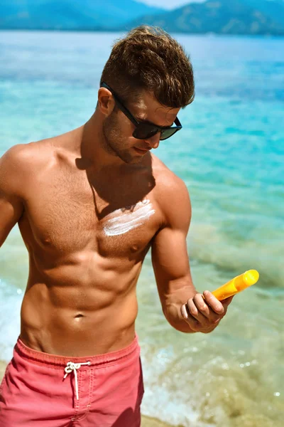 Man Tanning Using Sun Block Body Cream On Summer Beach