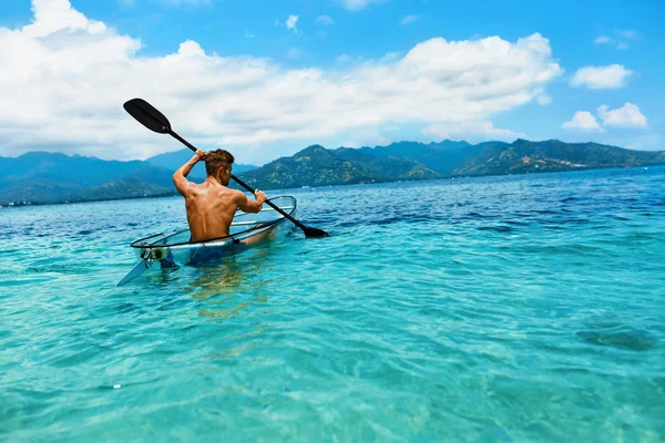 Sommerreise-Kajak. Mann paddelt durchsichtiges Kajak im Meer — Stockfoto