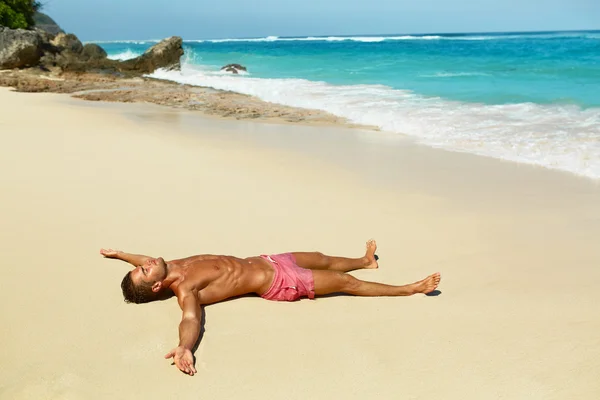 Il corpo dell'uomo sulla spiaggia. Estate maschio sdraiato sulla sabbia al resort — Foto Stock