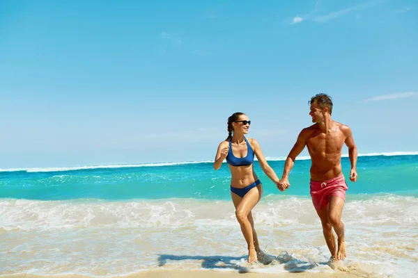 Un par de diversión en la playa. Gente romántica enamorada corriendo en el mar —  Fotos de Stock