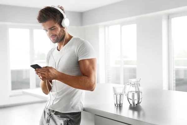 Man Listening To Music In Headphones Menggunakan Mobile Phone Indoors — Stok Foto