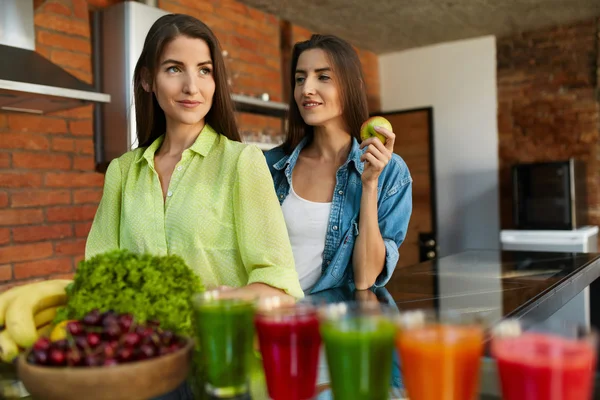 Sund mad til kost. Kvinder spiser frugt, Smoothie i køkkenet - Stock-foto