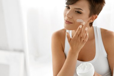 Beauty Skin Care. Beautiful Woman Applying Cosmetic Face Cream clipart