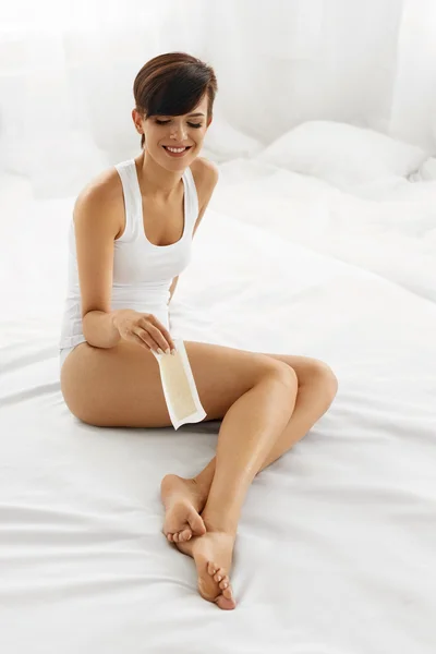 Depilación. Hermosa mujer encerando piernas largas con tira de cera — Foto de Stock