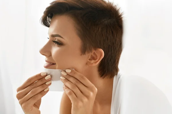 Hautpflege. Frau reinigt Gesicht mit Öl absorbierenden Papieren. — Stockfoto