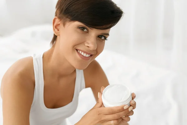 Cuidado com a pele. Mulher feliz bonita segurando creme de rosto, loção — Fotografia de Stock