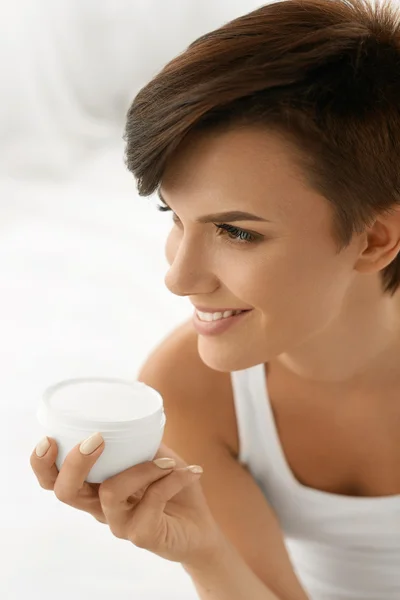 Cuidado com a pele. Mulher feliz bonita segurando creme de rosto, loção — Fotografia de Stock