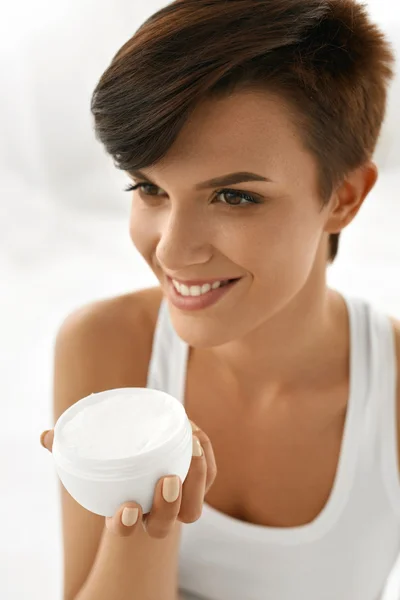 Cuidado de la piel. Hermosa mujer feliz sosteniendo crema facial, Loción — Foto de Stock