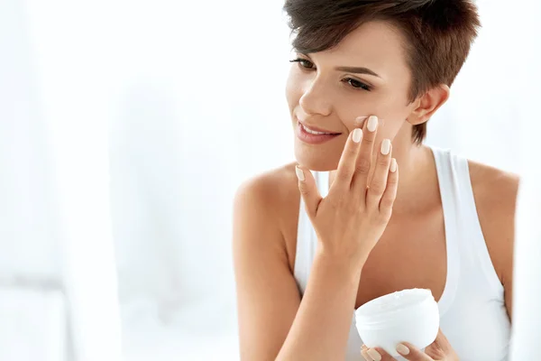 Cuidados com a pele beleza. Mulher bonita aplicando creme facial cosmético — Fotografia de Stock