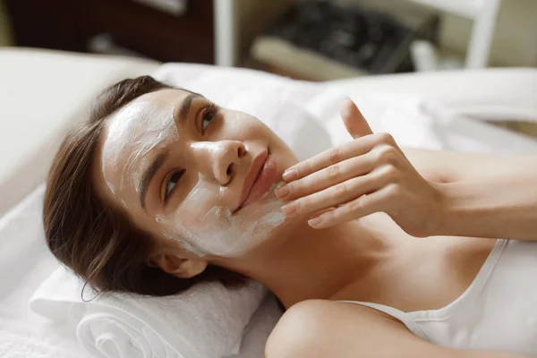 Уход за кожей лица. Красивая женщина с косметической маской на лице в спа — стоковое фото