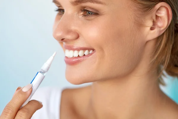 Dientes blancos sanos. Hermosa mujer sonriente usando pluma blanqueadora — Foto de Stock