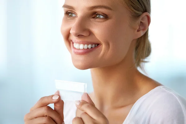 Branqueamento dos dentes. Mulher sorridente bonita segurando Whitening Strip — Fotografia de Stock