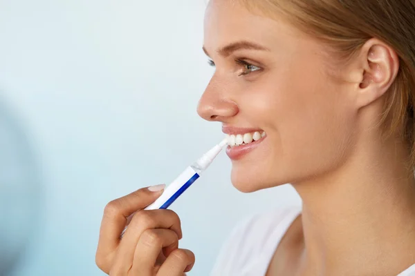 Λεύκανση δοντιών. Όμορφη γυναίκα χρησιμοποιώντας δόντια λεύκανση στυλό — Φωτογραφία Αρχείου
