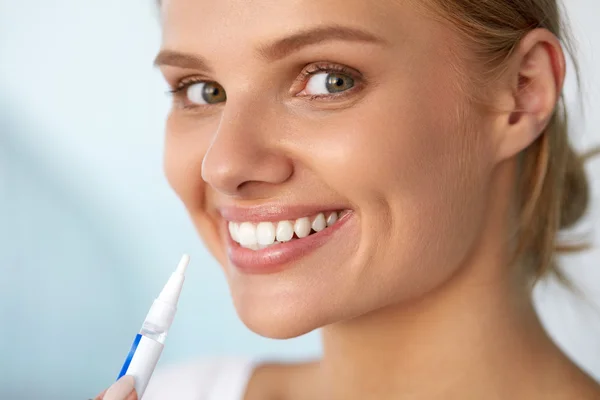 Dientes blancos sanos. Hermosa mujer sonriente usando pluma blanqueadora — Foto de Stock