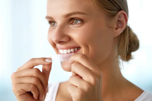 Mujer con dientes blancos sanos usando tira blanqueadora de dientes — Foto de Stock