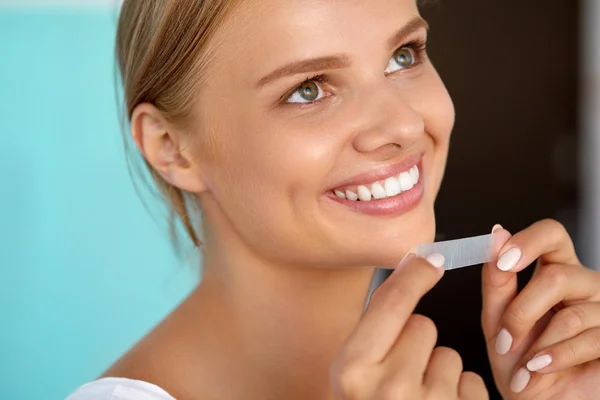 Mujer con dientes blancos sanos usando tira blanqueadora de dientes —  Fotos de Stock