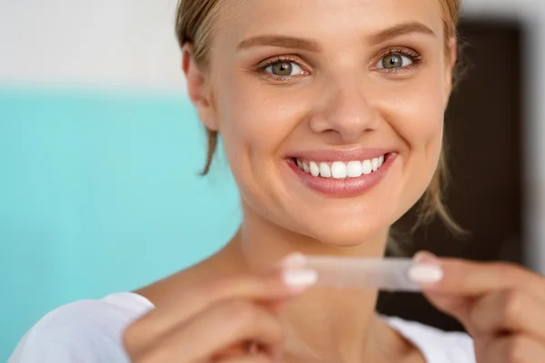 Mujer con dientes blancos sanos usando tira blanqueadora de dientes —  Fotos de Stock