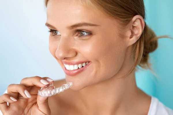 Mulher sorridente com sorriso bonito usando dentes branqueamento bandeja — Fotografia de Stock