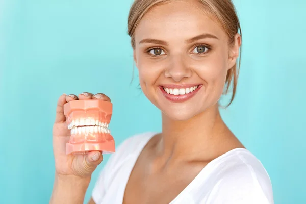 Женщина с красивой улыбкой, здоровые зубы держат стоматологическую модель — стоковое фото