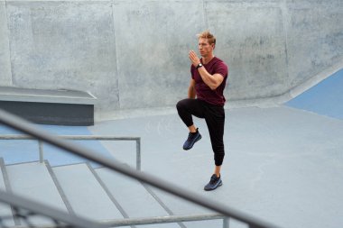 Dışarıdaki Beton Merdivenler 'in yanında koşan genç adam. Yakışıklı beyaz tenli güçlü kaslı sporcu. Moda sporu kıyafetleri, yoğun antrenmandan önce ısınıyor..