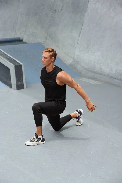 Jovem se aquecendo contra a parede de concreto ao ar livre. Bonito desportista caucasiano com corpo muscular forte na moda Sportswear Exercício antes do treino intenso. — Fotografia de Stock