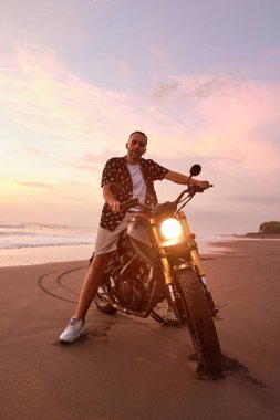 Ocean Beach 'teki Motosikletli Adam Güzel Tropik Gün Batımında. Endonezya, Bali 'de Kum Sahili' nde Motorsikletli Yakışıklı Bakış.
