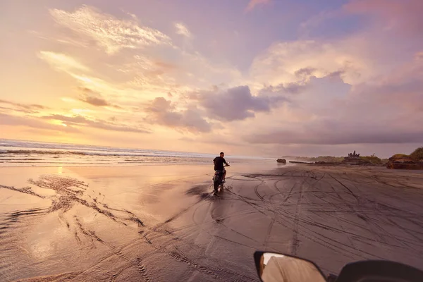 Man And Motorcycle On Ocean Beach At Beautiful Tropical Sunset (em inglês). Silhueta de motociclista em moto na costa arenosa perto do mar em Bali, Indonésia. — Fotografia de Stock