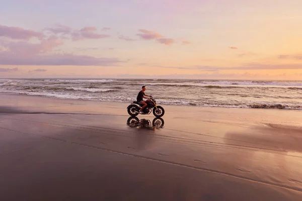Man And Motorcycle On Ocean Beach At Beautiful Tropical Sunset (em inglês). Silhueta de motociclista em moto na costa arenosa perto do mar em Bali, Indonésia. — Fotografia de Stock