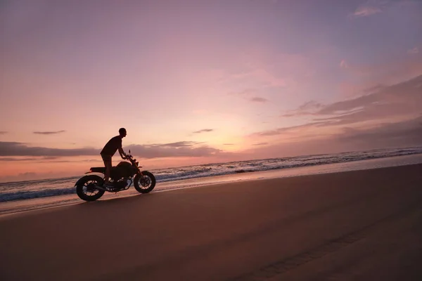 Homme et moto sur Ocean Beach au beau coucher de soleil tropical. Silhouette de motard sur la moto sur la côte sablonneuse près de la mer à Bali, Indonésie. — Photo