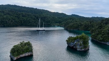 Raja Ampat Adalarındaki Triton Körfezi Turkuaz Denizi 'ndeki Tekne ve Yeşil Tropikal Ağaçlar. Geniş Açı Doğanın Havadan Görünümü, Pasifik Okyanusu ve Resimli Manzara Papua, Endonezya.