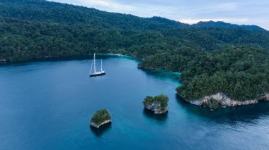 Triton Körfezi 'nin Havadan Görünümü, Raja Ampat Adaları, Turkuaz Suyu ve Yeşil Tropikal Ağaçlı Gölde Tekne. Geniş Açı Doğa: Pasifik Okyanusu ve Endonezya Papua 'da Çarpıcı Manzara.
