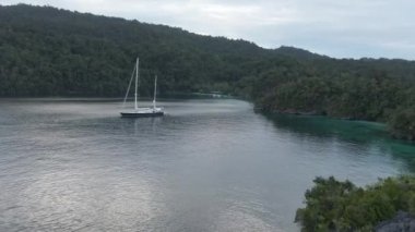 Triton Körfezi 'nin havadan görünüşü: Turkuaz Denizi' ndeki tekne ve Kaimana Adaları 'ndaki yeşil tropikal ağaçlar. Geniş Açı Doğa; Pasifik Okyanusu ve Resimli Manzara Papua, Endonezya.