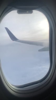 Mavi Gökteki Bulutların Üzerinde Uçan Uçak. Uçakların Penceresinden Güzel Görünümün Dikey Videosu; Bulutlu Arkaplanda Kanat.