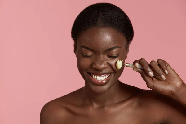 Portret Bliska Pięknej Afrykańskiej Dziewczyny Masuje Twarz Jadeitowym Wałkiem Uśmiechnięta — Zdjęcie stockowe