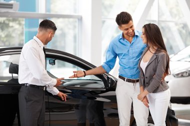Car Salesman Invites Customers at Showroom. clipart