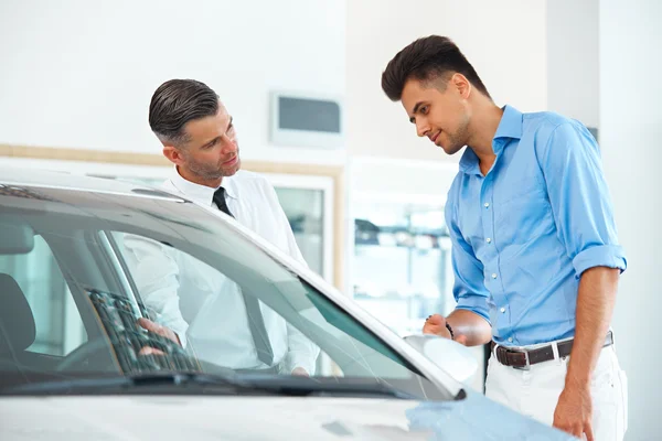 Car Sales Consultant Showing a New Car to a Potential Buyer — Stock Photo, Image