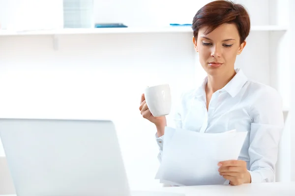 Geschäftsfrau trinkt Kaffee und liest Zeitung — Stockfoto