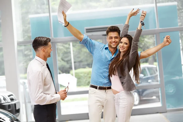 Autoverkäufer lädt Kunden in Showroom ein. — Stockfoto