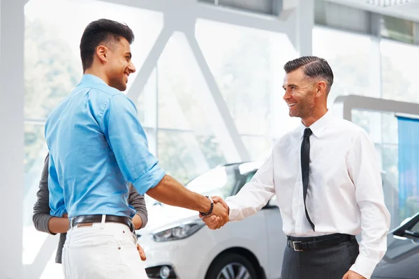 Coppia è incontro con venditore in salone di auto — Foto Stock