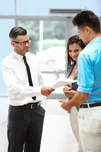 Venditore di auto invita i clienti presso lo showroom . — Foto Stock