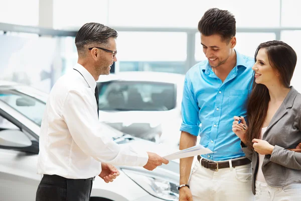 Car Salesman Invites Customers at Showroom. — Stock Photo, Image