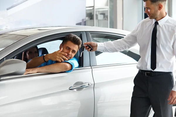 Продавец автомобилей вручает новый ключ от автомобиля клиенту — стоковое фото